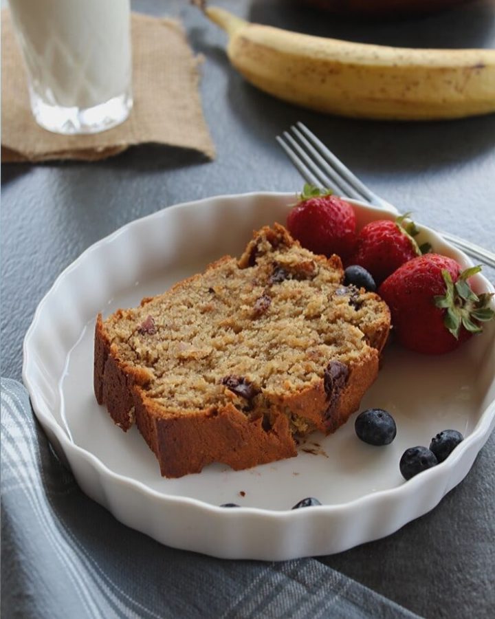 moist banana bread topped with chocolate chips and served with some berries