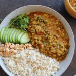 green moong dal curry served with rice, peanuts and cucumber.