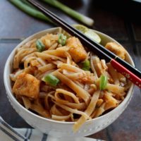 vegan pad thai noodles served in a white bowl with chap sticks