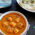paneer butter masala served in a white bowl with naan and rice