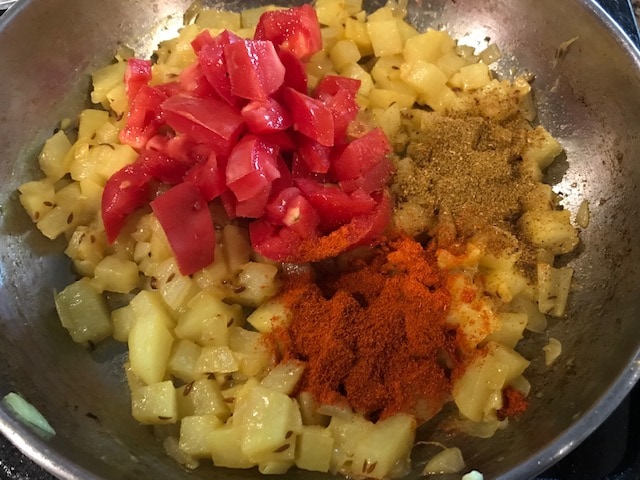 adding tomato and spices to the pan
