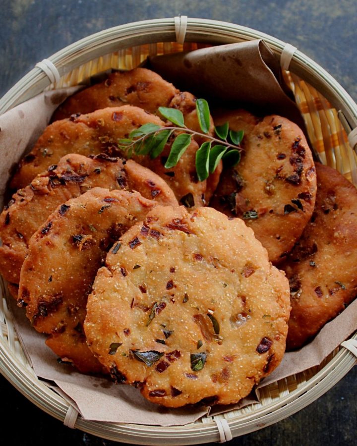 maddur vada served in a small basket and curry leaves on the side