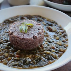 ragi sankati served with amaranth dal in a white plate topped with curry leaves