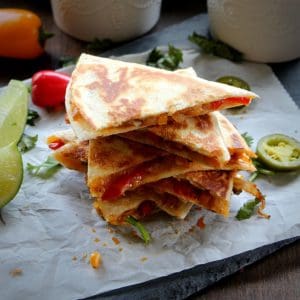 stacked veggie quesadilla served with lime wedges, sour cream and salsa