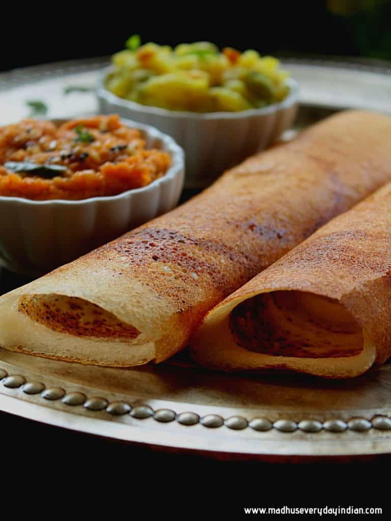 crispy dosa served with onion chutney and potato fry in a plate