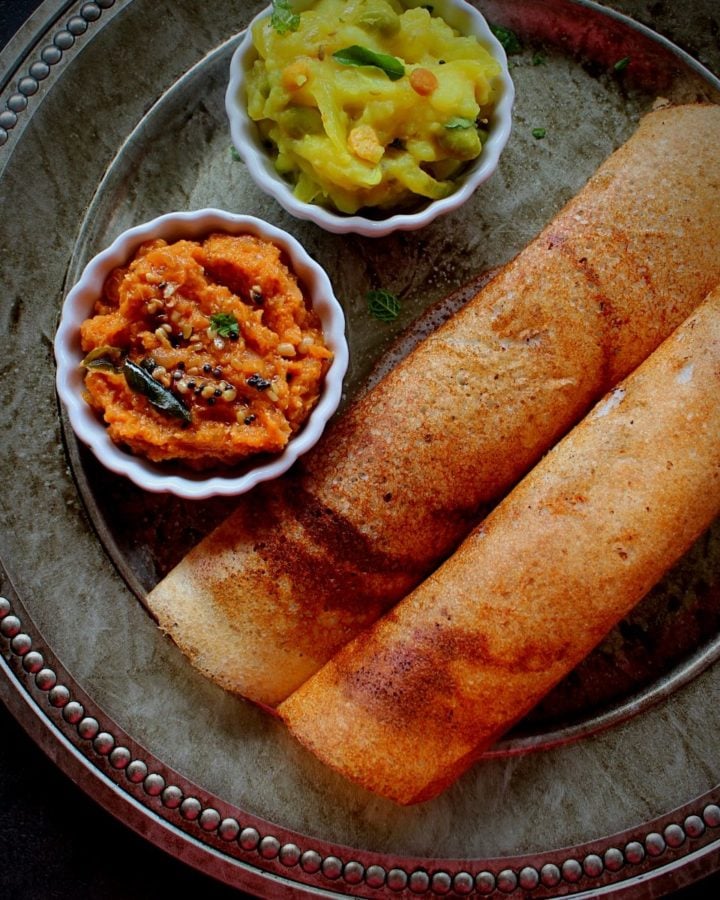 crispy dosa served with onion chutney and potato fry in a plate