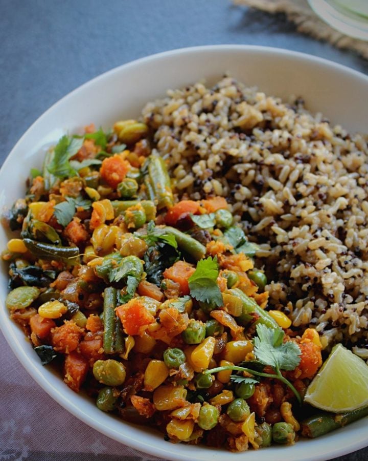 quinoa and brown rice served with mixed vegetable fry on a white plate with some lime