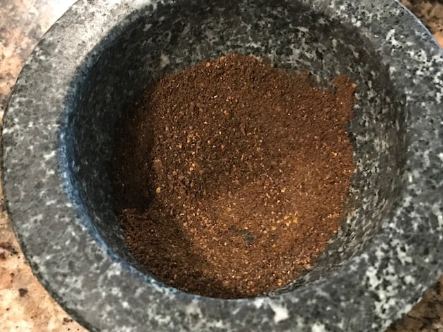 powdered fenugreek and mustard seeds in a mortar