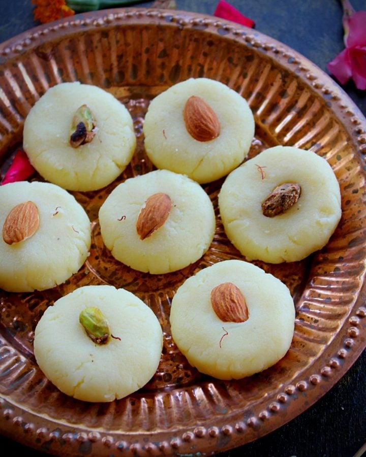 malai peda swerved in a plate with almonds and few flowers for garnish