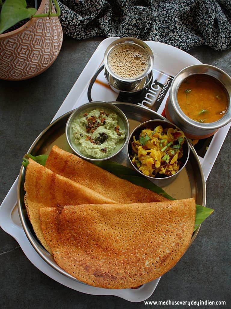 instant wheat dosa served in  asteel plate with coconut chutney, potato fry, sambar and coffee