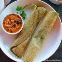 2 green moong dal dosa folded served with ginger chutney in a white plate