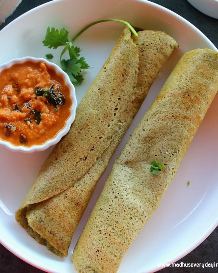 2 green moong dal dosa folded served with ginger chutney in a white plate