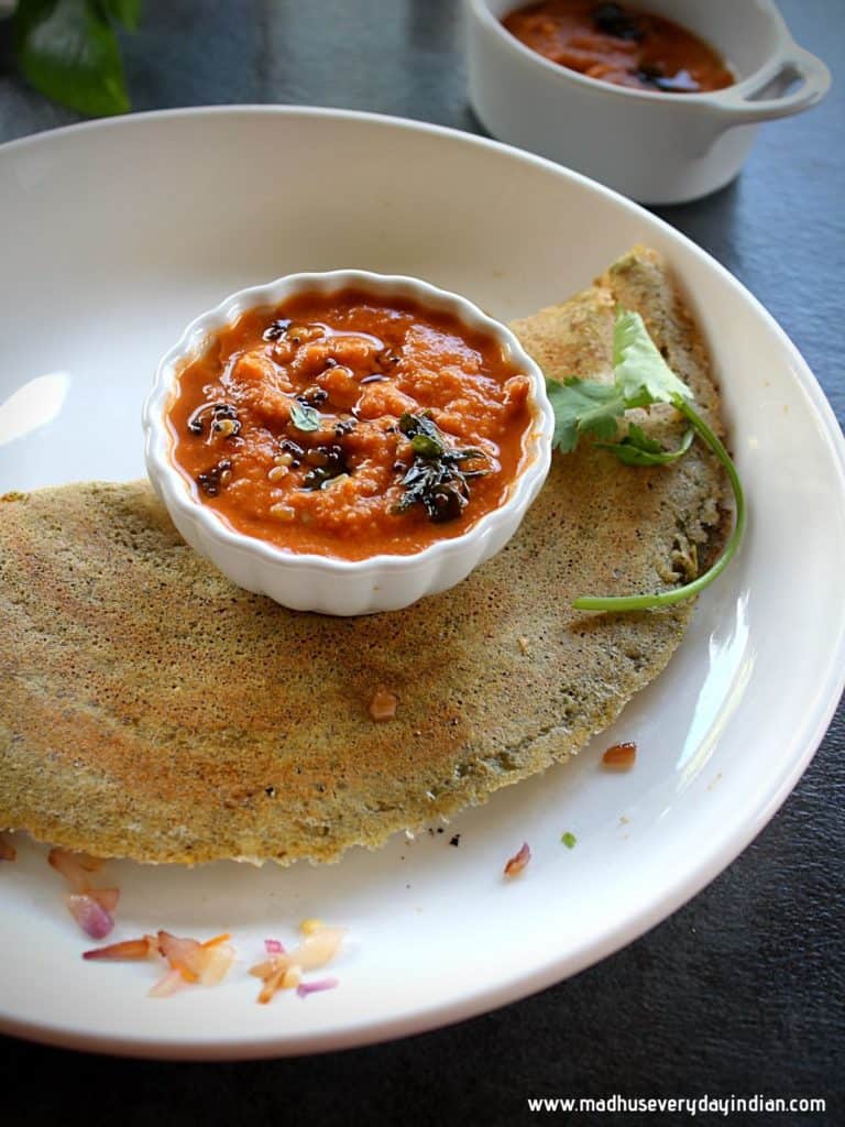 moong dal dosa folded served with ginger chutney in a white plate