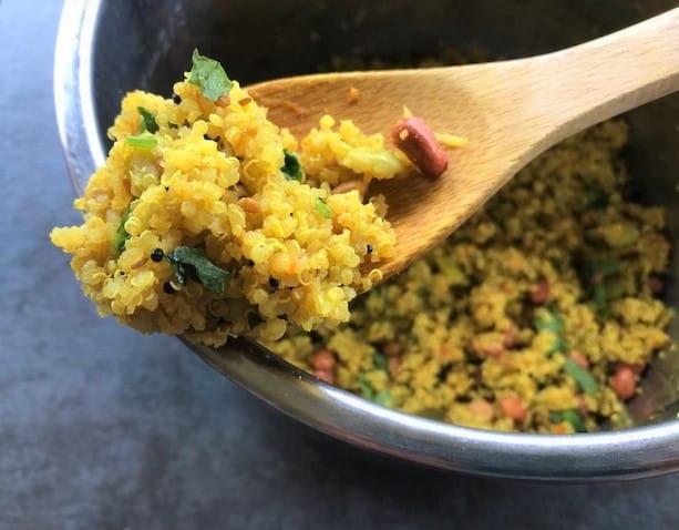 lemon quinoa on a wooden spoon with peanuts and coriander leaves