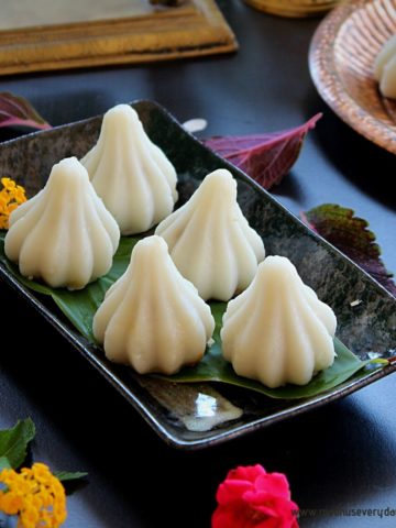 steamed modak served in a black plate and flowers on the side
