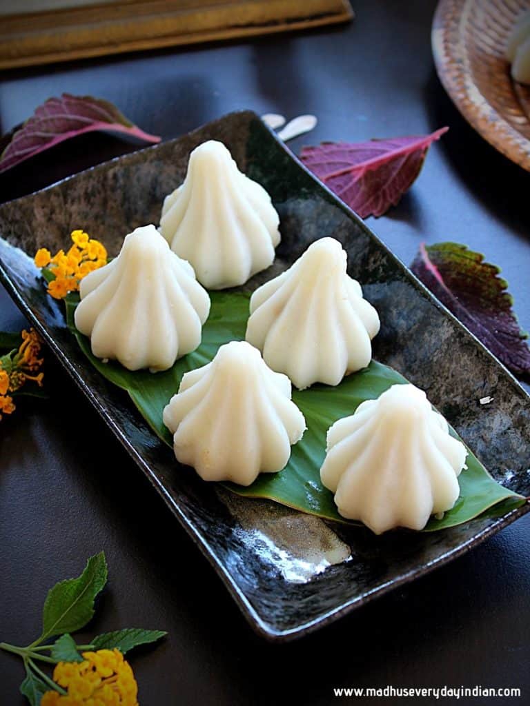 steamed modak served in a black plate and flowers on the side