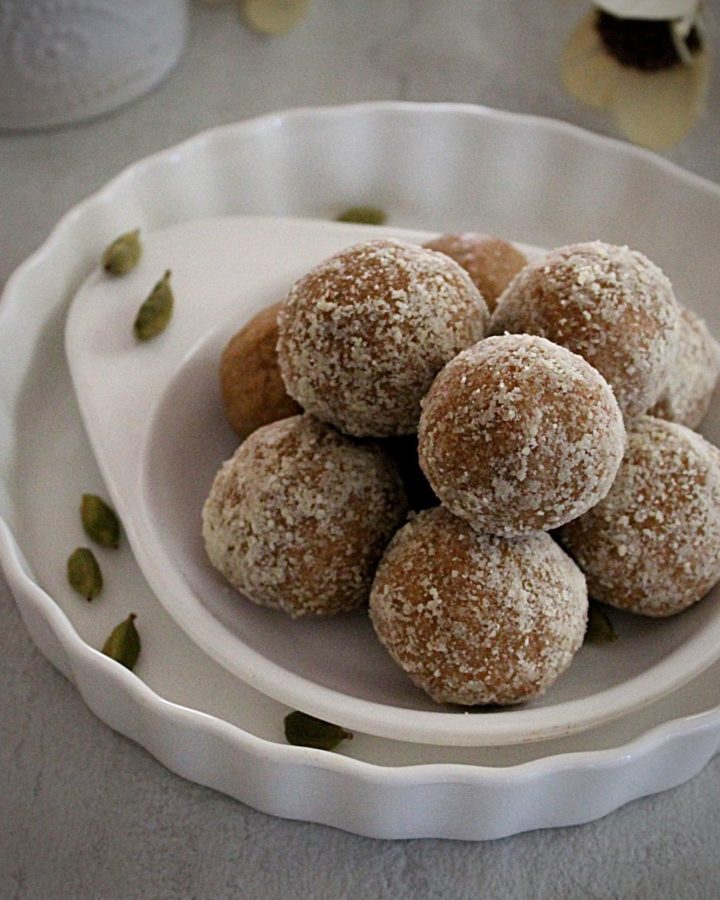 almond ladoo made with almond flour arranged in a double white place and garnished with cardamom.