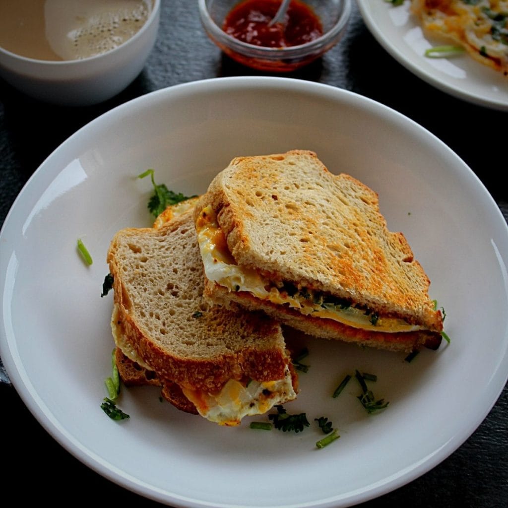 easy egg sandwich served in a white bowl with coffee and chili sauce