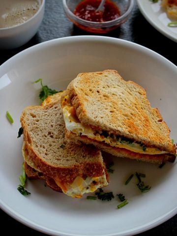 easy egg sandwich served in a white bowl with coffee and chili sauce