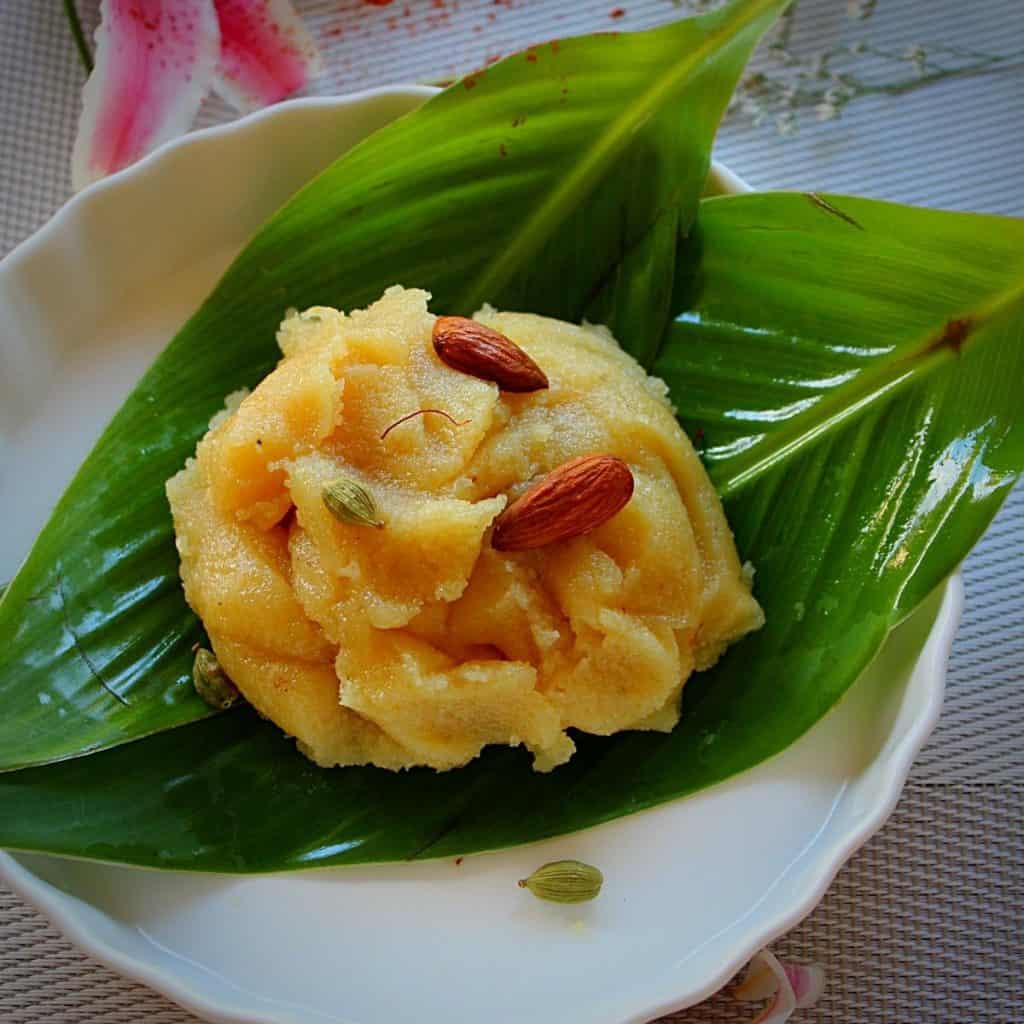 badam halwa served with green leaves towhole almonds, saffron and cardamom