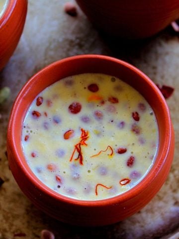 badam milk served in clay pots topped with saffron and nuts