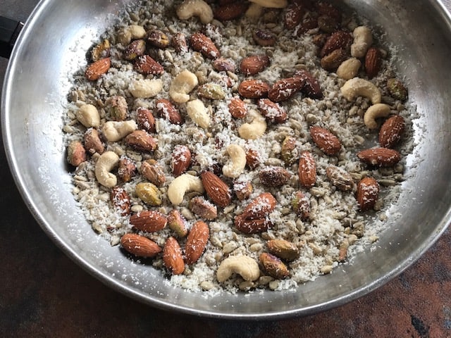 roasted nuts, coocnut and seeds in a steel pan