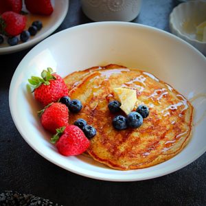 pumpkin pancakes drizzled with maple syrup and garnished with butter and berries