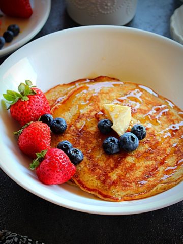 pumpkin pancakes drizzled with maple syrup and garnished with butter and berries