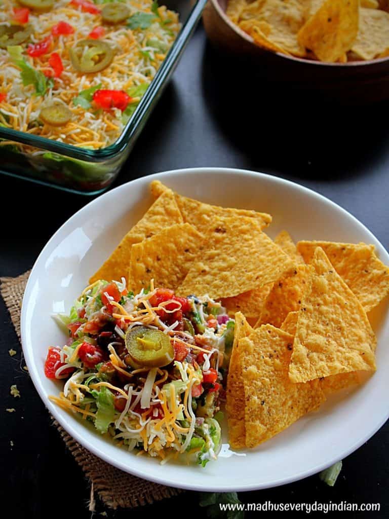 7 layer dip served with tortilla chips in a white plate