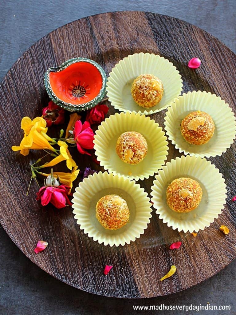 coconut ladoo served in cupcake liner and served in a wooden plate garnishded with some rose petals