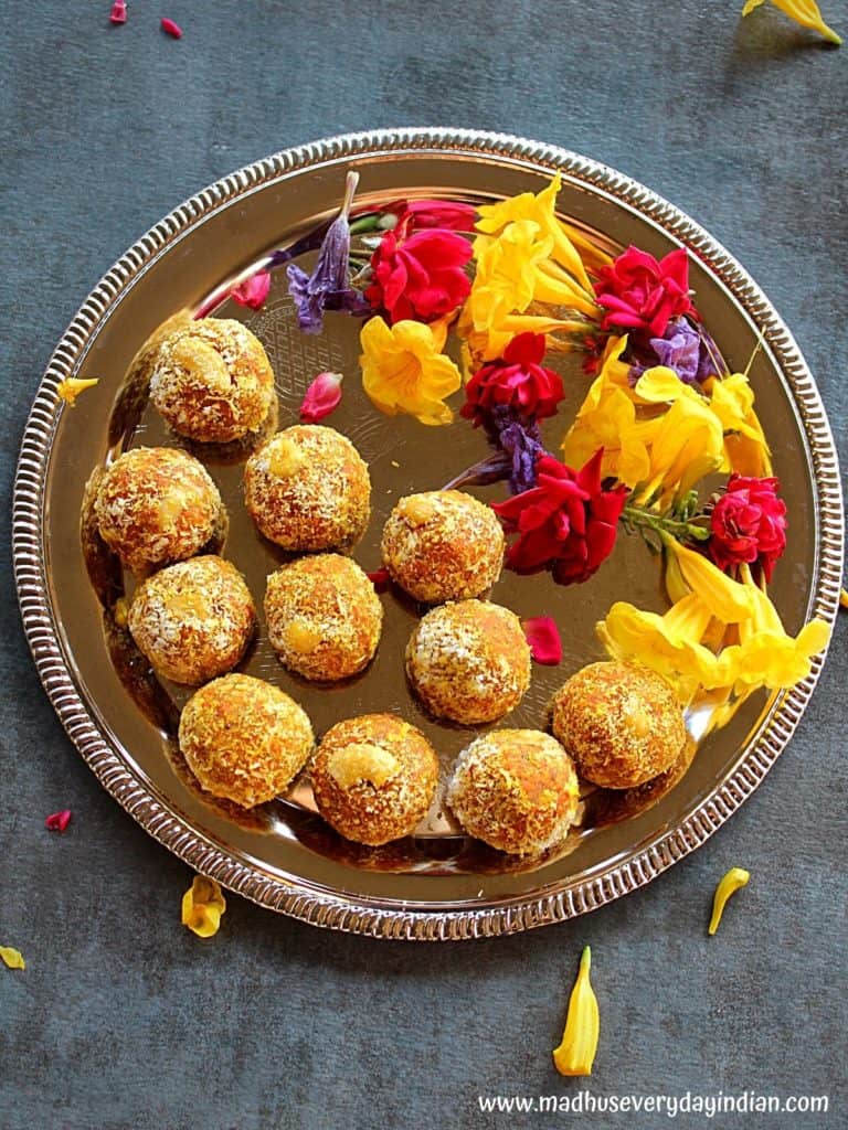 carrot ladoo served in a sliver plate with colored flowers