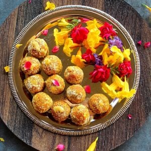 carrot ladoo served in a sliver plate with colored flowers