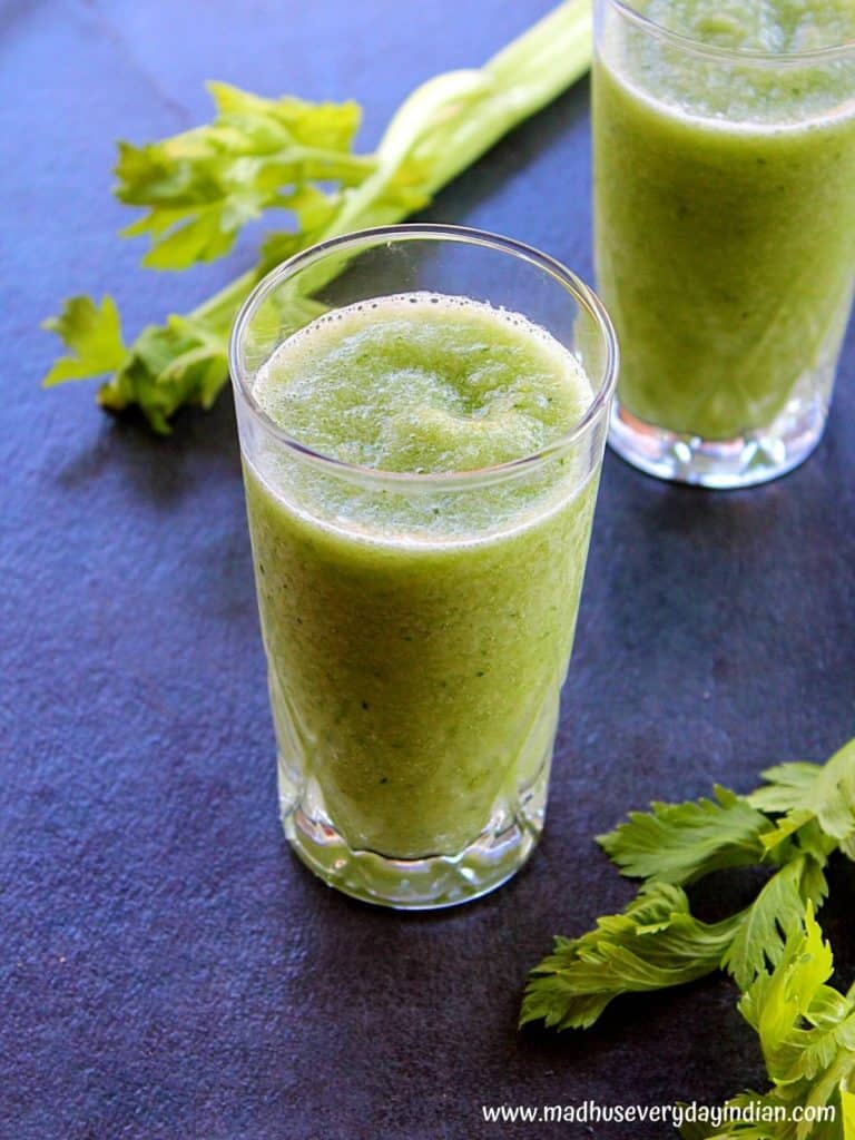 celery smoothie served in two glass cups with celery stalks