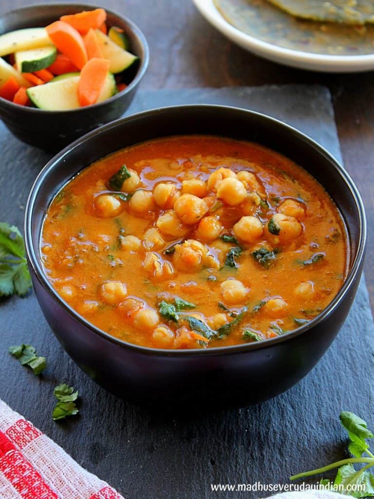 instant pot chickpea coocnut curry with spinach served in a large black bowl garnished with cilantro and salad