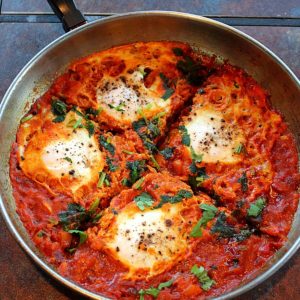 Indian style Shakshuka served in a steel saute pan garnished with cilantro
