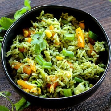 indian style spinach fried rice served in a black bowl garnished with coriander leaves