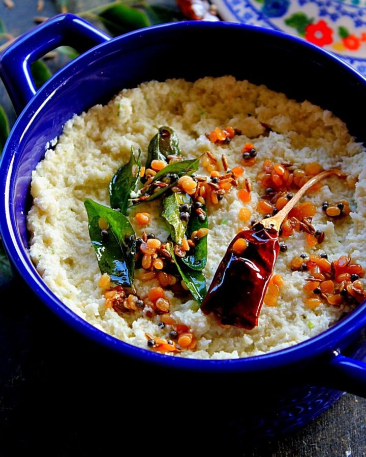 desiccated coconut chutney served in a blue bowl with a temeoring of mustard seedsm dal, curry leaves and dry red chili