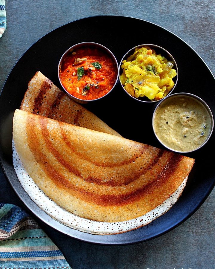 rice flour dosa served in a black palte with two chutney's and potato fry