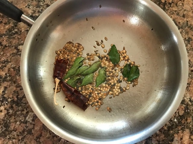 temepring with oil, mustard seeds, hing, curry leaves, dal, dry redchili done in a small steel pan