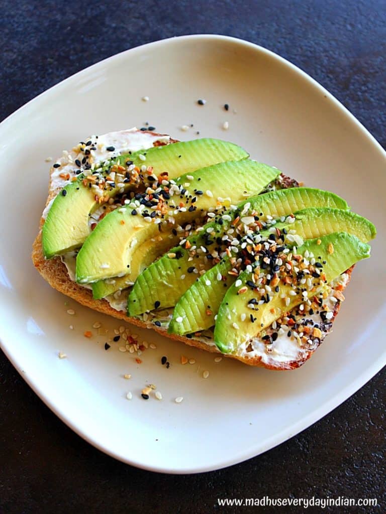 everything but bagel seasoning toast with avocado slices served in a white plate