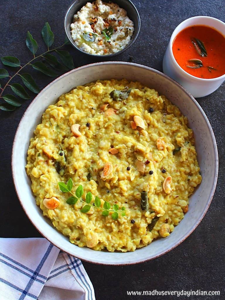 oats ven pongal served in a large plate garnished with curry leaves and served with chutney and gojju