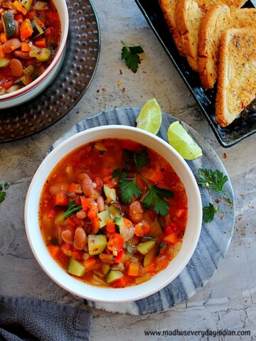 vegetable soup with pinto beans served in a large bowl garnished with parsley and lemon
