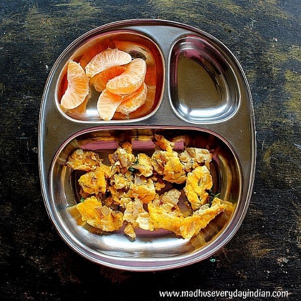scrambled egg served with orange in a steel partition plate