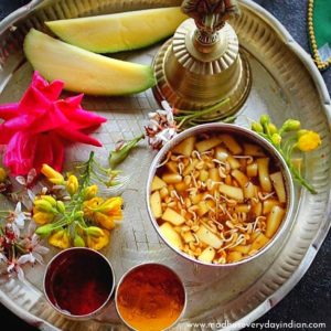 ugadi pachadi served in a sliver plate with banana and flowers.