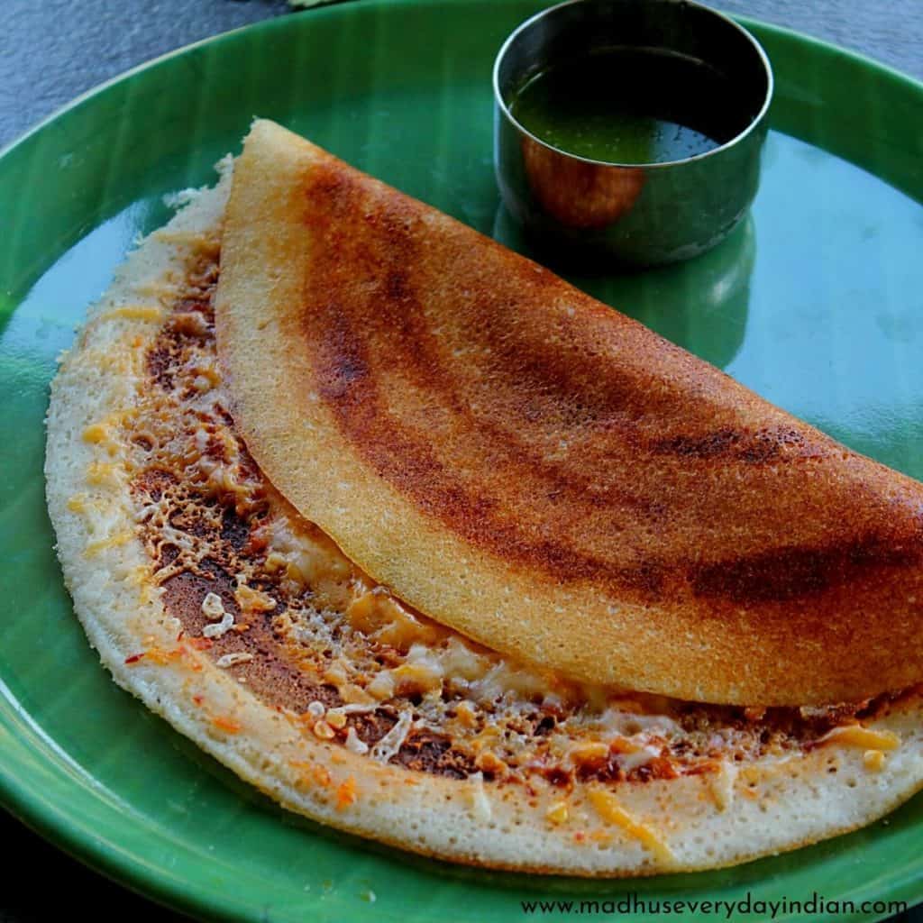 chili cheese dosa served with green chutney in a green plate