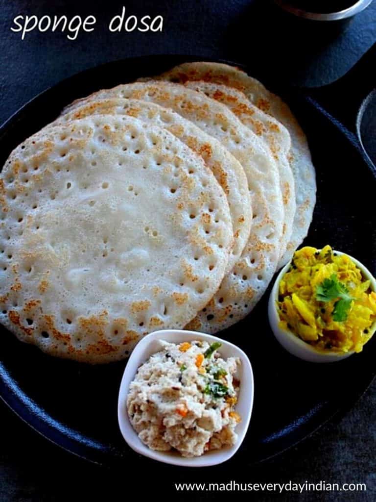 5 poha dosa served in a cast iron pan with potato fry and chutney.