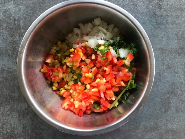 corn, onion, jalapeno and pepper added in a steel bowl.