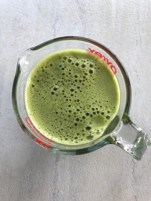 green juice poured in a glass cup.