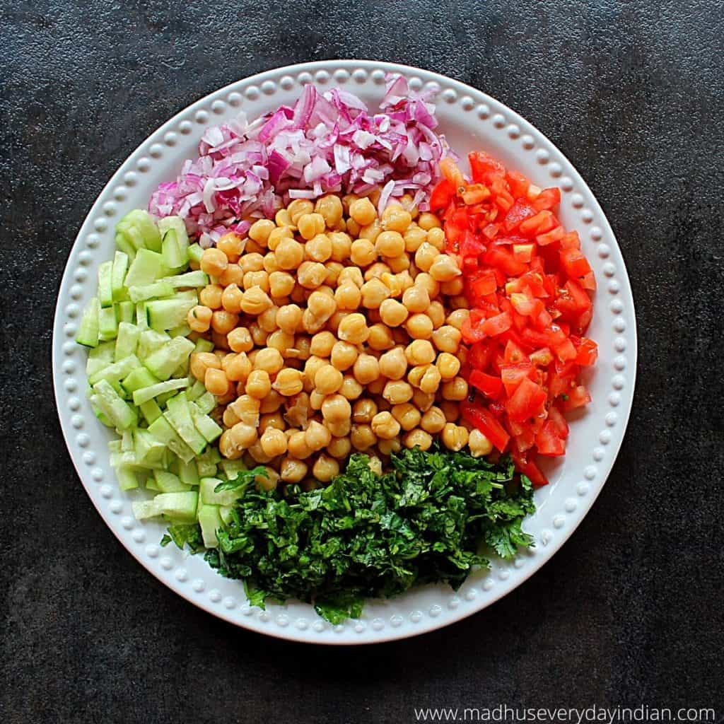 boiled chickpeas, onion, tomato, cucumber and coriander arranged in a  white plate