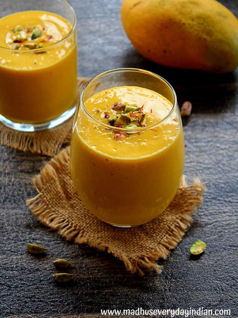 healthy mango lassi with dates served ina  glass cup garnished with nuts and saffron.